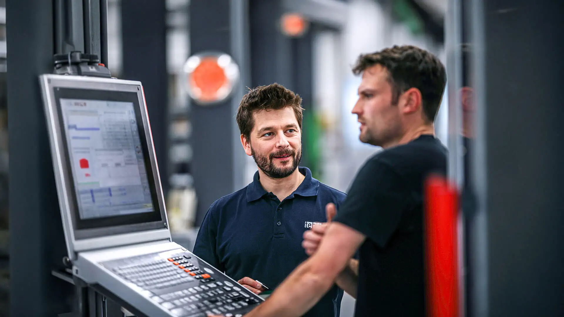Due tecnici davanti a un centro di lavoro CNC con il software Tebis
